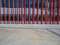 a concrete structure made into rows of orange and yellow poles are on a cement sidewalk