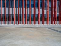 a concrete structure made into rows of orange and yellow poles are on a cement sidewalk