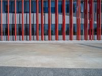 a concrete structure made into rows of orange and yellow poles are on a cement sidewalk