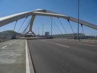 a truck driving across a bridge near a street corner near buildings and a bridge with many cables