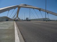 a truck driving across a bridge near a street corner near buildings and a bridge with many cables