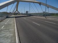 a truck driving across a bridge near a street corner near buildings and a bridge with many cables