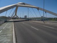 a truck driving across a bridge near a street corner near buildings and a bridge with many cables