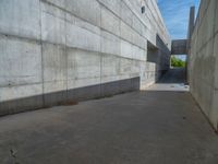 the empty parking lot in front of a wall with apartment buildings on it and a skateboarder on a ramp