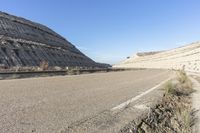 the road is paved with long gravel and mountains in the distance along the side, with dirt on both sides