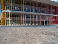 a concrete structure made into rows of orange and yellow poles are on a cement sidewalk