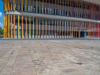 a concrete structure made into rows of orange and yellow poles are on a cement sidewalk