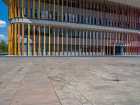 a concrete structure made into rows of orange and yellow poles are on a cement sidewalk