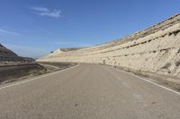 a large stretch of road with a mountain in the background and dry grass in between the middle