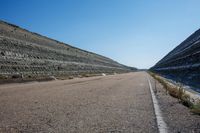 a long empty street leading into an open area next to a water hole on a hill side