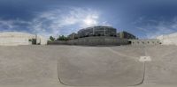 an artistic view of skateboards at a skate park with building in background and sun glaring across