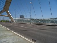 a truck driving across a bridge near a street corner near buildings and a bridge with many cables