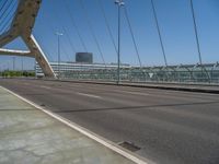 a truck driving across a bridge near a street corner near buildings and a bridge with many cables