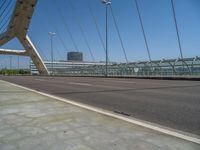 a truck driving across a bridge near a street corner near buildings and a bridge with many cables