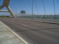 a truck driving across a bridge near a street corner near buildings and a bridge with many cables