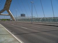 a truck driving across a bridge near a street corner near buildings and a bridge with many cables