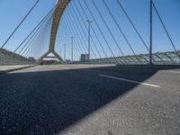 a truck driving across a bridge near a street corner near buildings and a bridge with many cables