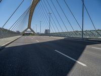 a truck driving across a bridge near a street corner near buildings and a bridge with many cables