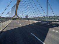 a truck driving across a bridge near a street corner near buildings and a bridge with many cables