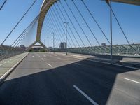 a truck driving across a bridge near a street corner near buildings and a bridge with many cables