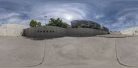 a skateboarder riding on a ramp near a cement building with other buildings behind