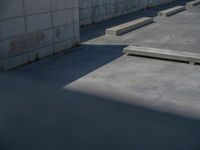 the empty parking lot in front of a wall with apartment buildings on it and a skateboarder on a ramp