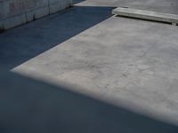 the empty parking lot in front of a wall with apartment buildings on it and a skateboarder on a ramp