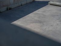 the empty parking lot in front of a wall with apartment buildings on it and a skateboarder on a ramp