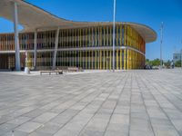 a concrete structure made into rows of orange and yellow poles are on a cement sidewalk