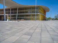 a concrete structure made into rows of orange and yellow poles are on a cement sidewalk