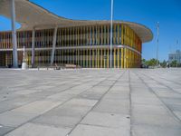 a concrete structure made into rows of orange and yellow poles are on a cement sidewalk