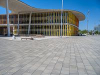 a concrete structure made into rows of orange and yellow poles are on a cement sidewalk