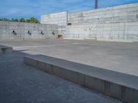 the empty parking lot in front of a wall with apartment buildings on it and a skateboarder on a ramp