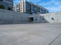 the empty parking lot in front of a wall with apartment buildings on it and a skateboarder on a ramp