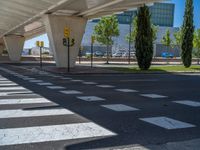 a car sitting at an empty street underneath a overpass overhang that contains a train stop, and cars and a pedestrian