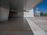 a white building with several steps and large glass panels in the facade is a mosaic that depicts a man