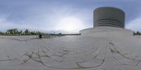 the reflection of a building is on a circular stone sculpture of a spiral design that appears to be made of bricks