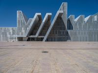 a white building with several steps and large glass panels in the facade is a mosaic that depicts a man