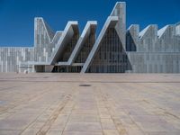 a white building with several steps and large glass panels in the facade is a mosaic that depicts a man