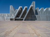 a white building with several steps and large glass panels in the facade is a mosaic that depicts a man