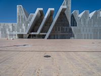 a white building with several steps and large glass panels in the facade is a mosaic that depicts a man