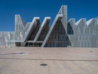 a white building with several steps and large glass panels in the facade is a mosaic that depicts a man