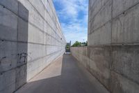 the empty parking lot in front of a wall with apartment buildings on it and a skateboarder on a ramp