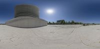 a circular sculpture sitting on top of sand next to tall buildings and people standing around