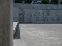 the empty parking lot in front of a wall with apartment buildings on it and a skateboarder on a ramp