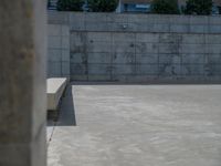 the empty parking lot in front of a wall with apartment buildings on it and a skateboarder on a ramp