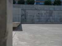 the empty parking lot in front of a wall with apartment buildings on it and a skateboarder on a ramp