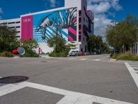 a zebra on the side of a building next to a road with trees and bushes