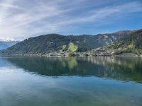 a body of water with lots of buildings around it and trees in the background and mountains in the distance