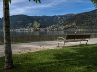 the park bench is located near the road on a sunny day by the water,